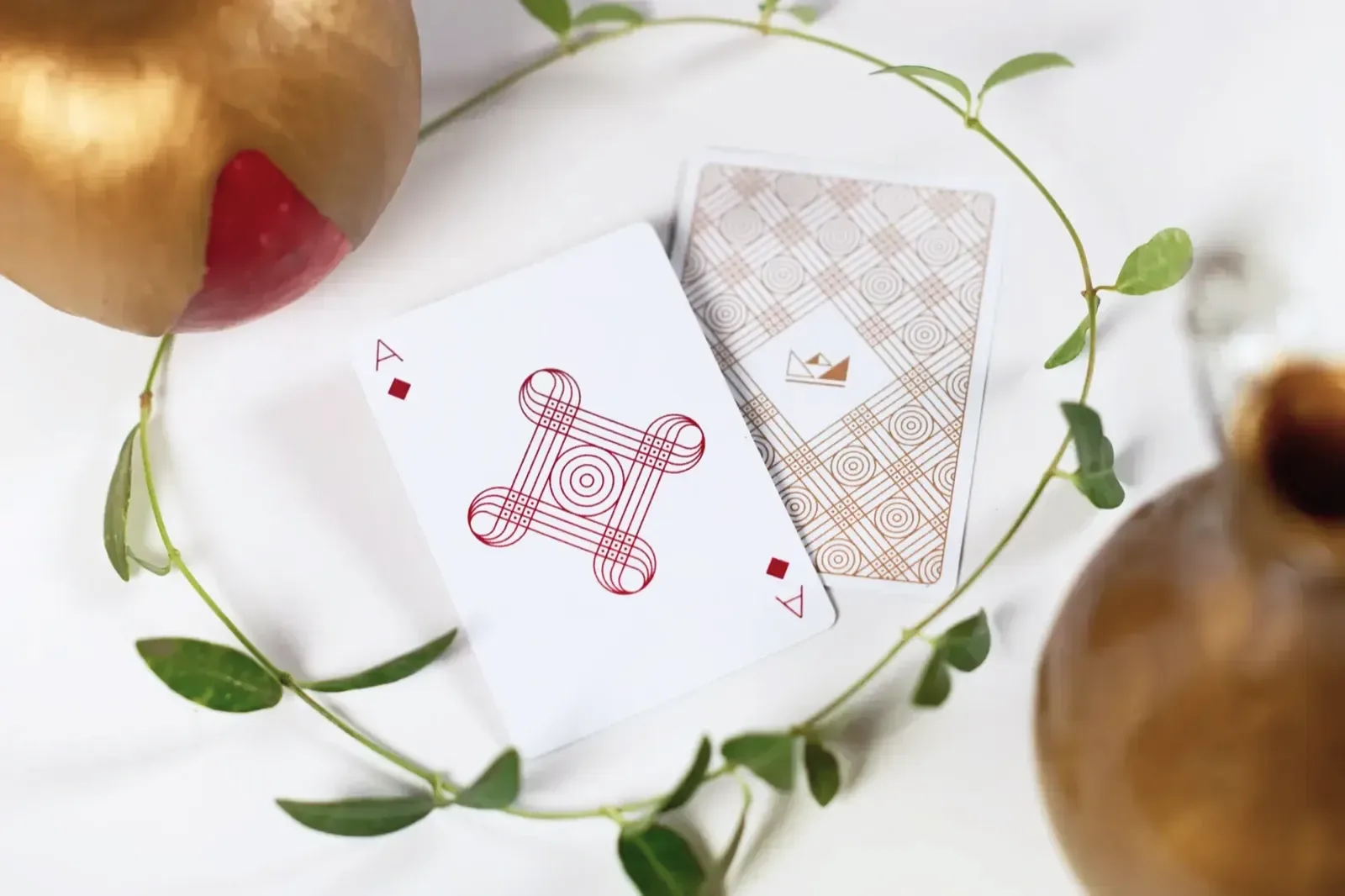 An ace of diamonds and a gold patterned card back, ringed by a trailing vine